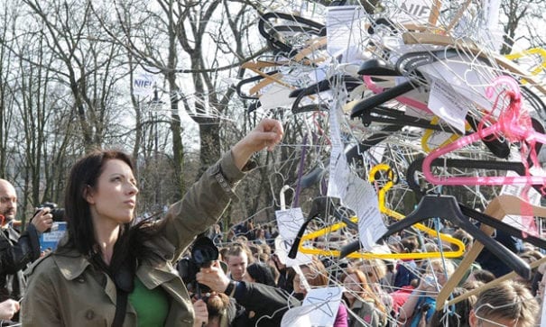 波蘭華沙街頭抗議民眾，手拿衣架，象徵非法墮胎。（圖片來源：nbcnews）